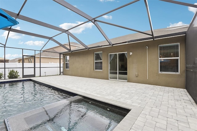 rear view of property with a lanai, a patio area, a fenced in pool, and stucco siding