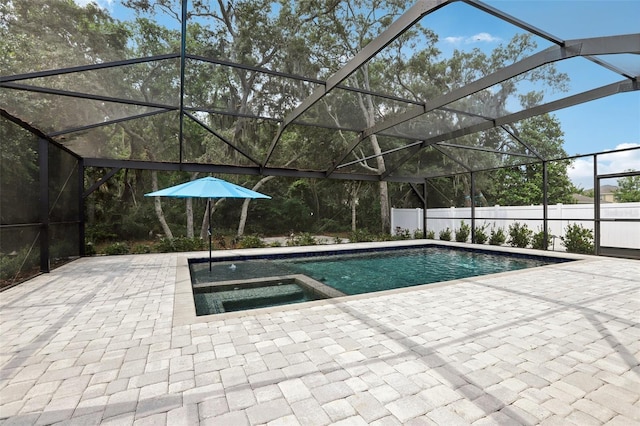 view of pool featuring glass enclosure, an in ground hot tub, and a patio area