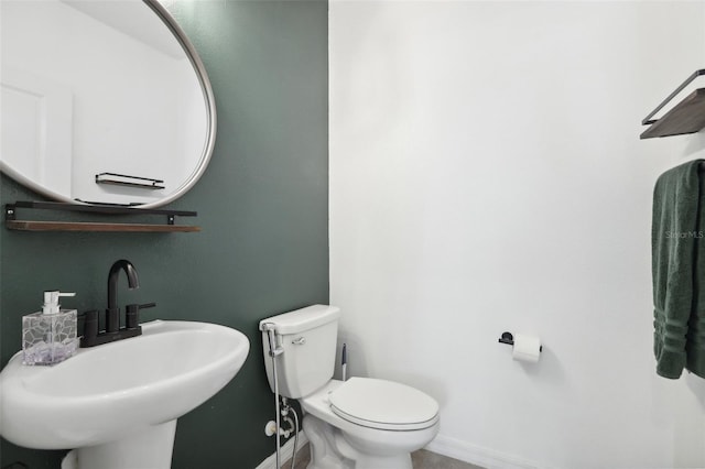 bathroom with a sink, toilet, and baseboards