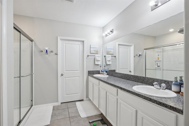 bathroom featuring tile patterned flooring, a sink, and a shower stall