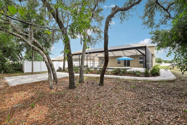 rear view of property featuring a lanai, fence, and driveway