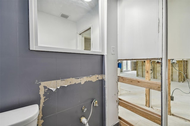 bathroom with toilet, tile walls, and water heater