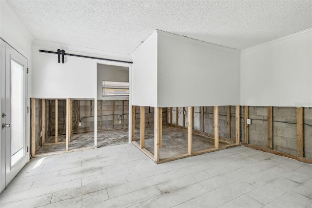 interior space with a barn door and a textured ceiling