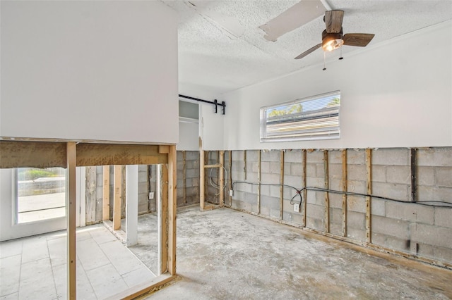 interior space featuring a textured ceiling, a barn door, ceiling fan, and a healthy amount of sunlight