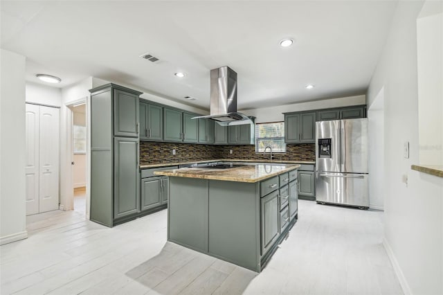 kitchen featuring backsplash, island range hood, stainless steel fridge with ice dispenser, light hardwood / wood-style floors, and a kitchen island