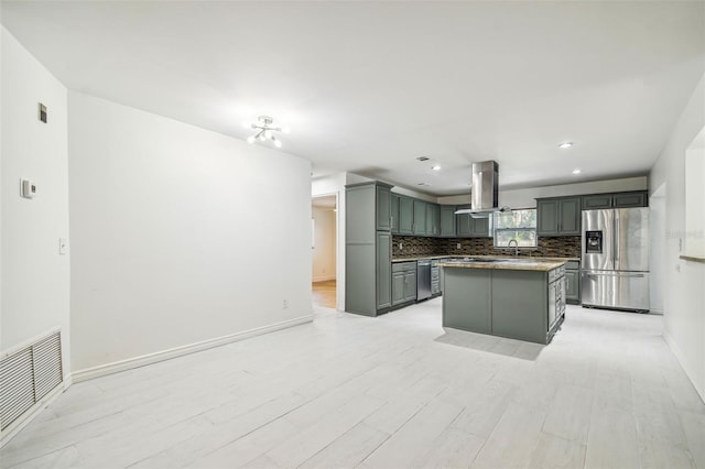 kitchen featuring gray cabinetry, stainless steel refrigerator with ice dispenser, island exhaust hood, a kitchen island, and light wood-type flooring