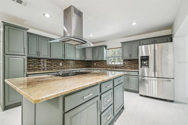 kitchen with light stone countertops, black electric stovetop, island range hood, stainless steel fridge with ice dispenser, and a center island