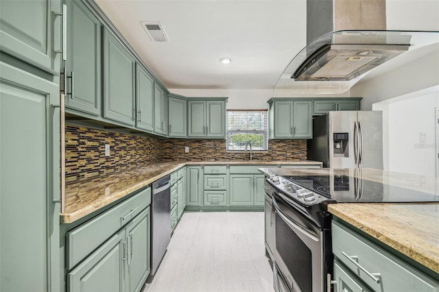 kitchen with light stone countertops, backsplash, stainless steel appliances, sink, and green cabinets