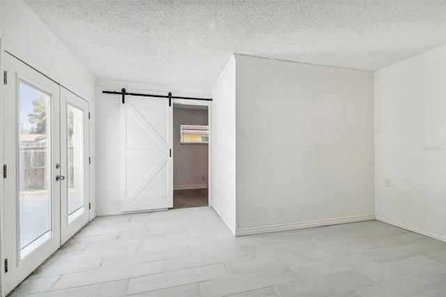 spare room with a barn door, french doors, and a textured ceiling