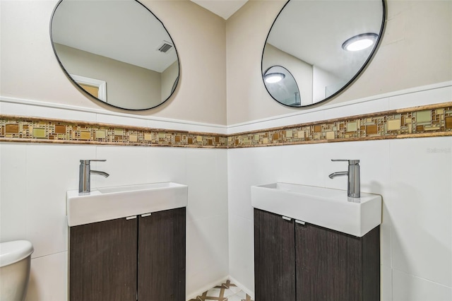 bathroom with vanity, tile walls, and toilet