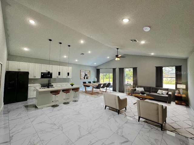 tiled living room with ceiling fan and vaulted ceiling