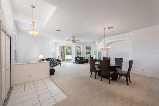 dining area with light carpet, a textured ceiling, and ceiling fan with notable chandelier