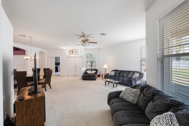 living room featuring carpet floors and ceiling fan with notable chandelier