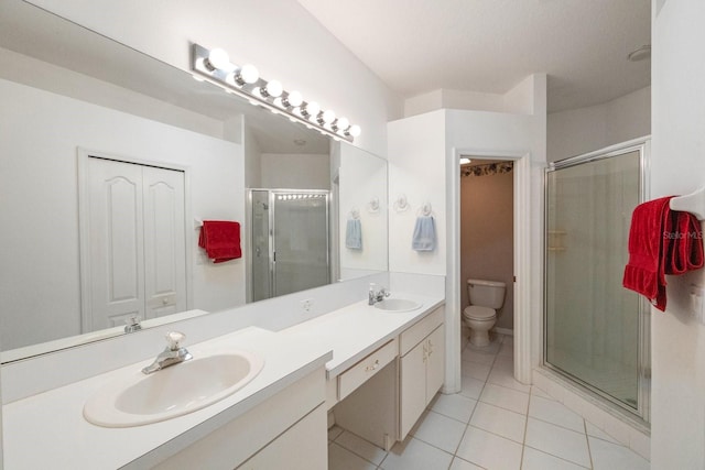 bathroom with dual sinks, tile flooring, vanity with extensive cabinet space, a shower with shower door, and toilet