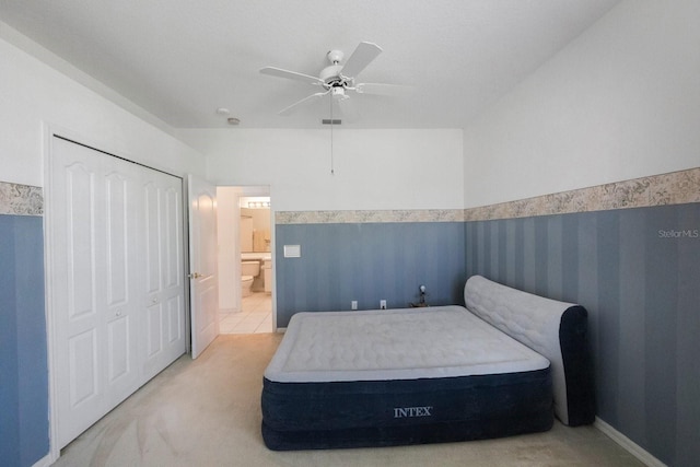 bedroom featuring ceiling fan, a closet, light carpet, and ensuite bathroom