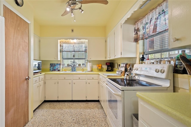 kitchen featuring backsplash, white range with electric stovetop, white cabinetry, and sink