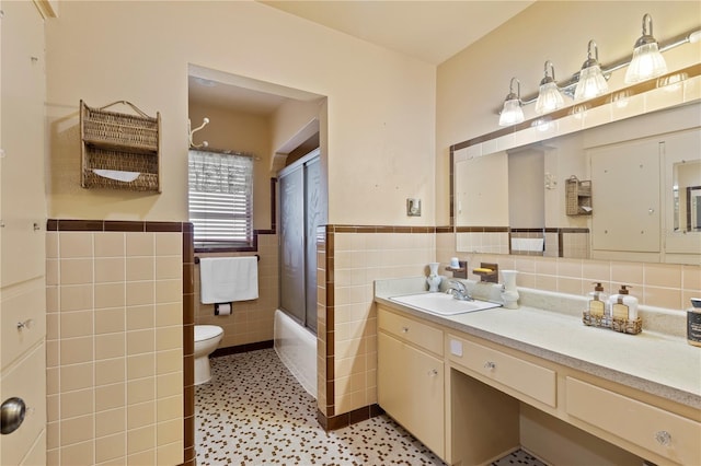 full bathroom featuring vanity, tile walls, enclosed tub / shower combo, tile patterned flooring, and toilet