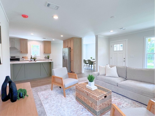 living room featuring plenty of natural light, ornamental molding, and light wood-type flooring