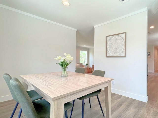 dining space featuring ornamental molding and wood-type flooring