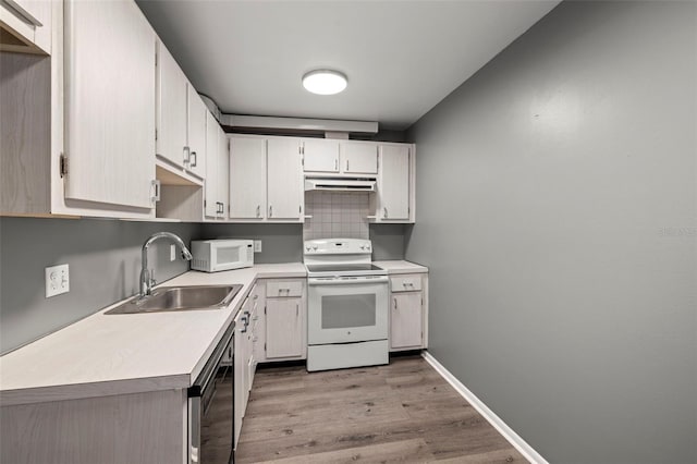 kitchen with tasteful backsplash, white appliances, wood-type flooring, sink, and white cabinets