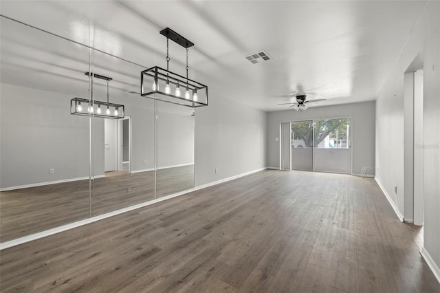 interior space featuring ceiling fan with notable chandelier and dark wood-type flooring