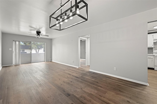 unfurnished living room with ceiling fan with notable chandelier and dark hardwood / wood-style flooring