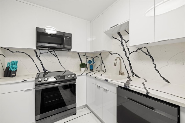 kitchen with stainless steel appliances, white cabinets, sink, and light tile floors