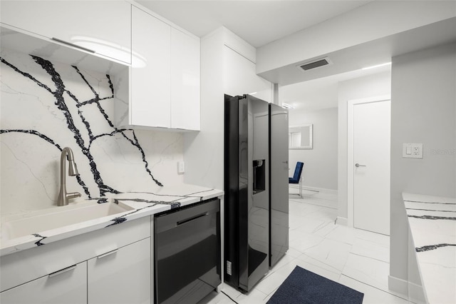 interior space with white cabinetry, light tile flooring, stainless steel fridge, and black dishwasher