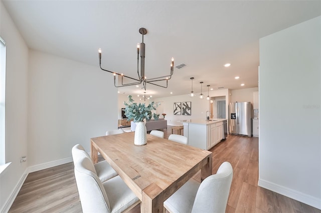 dining room featuring a notable chandelier, sink, and light hardwood / wood-style flooring