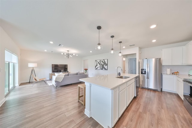 kitchen featuring light wood-type flooring, sink, a kitchen island with sink, white cabinetry, and appliances with stainless steel finishes