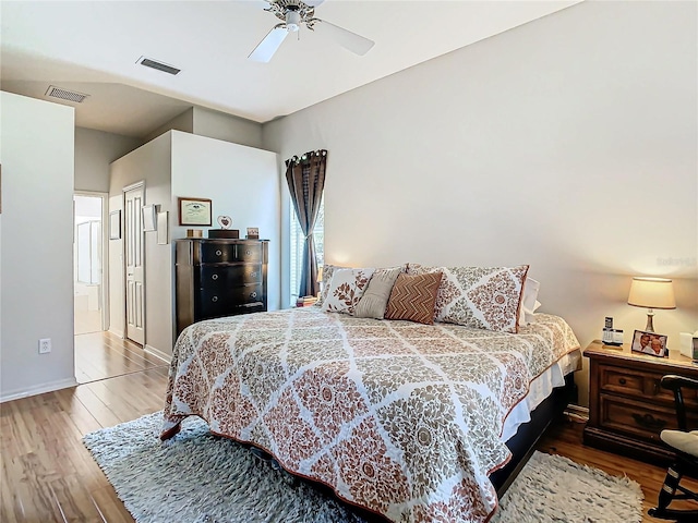 bedroom with ensuite bath, ceiling fan, and hardwood / wood-style flooring