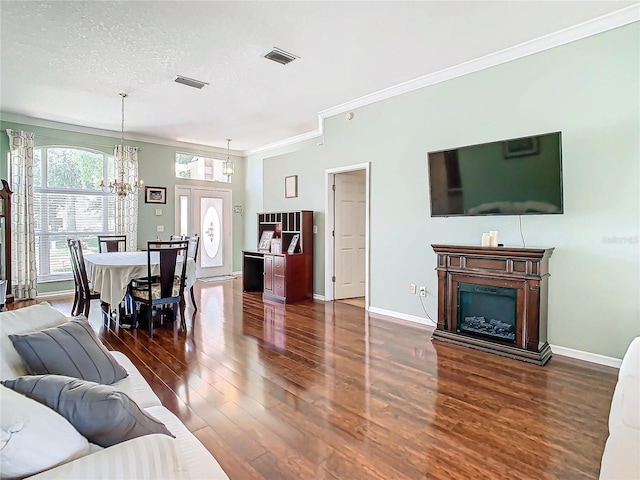 living room with crown molding, dark wood-type flooring, a textured ceiling, and a notable chandelier