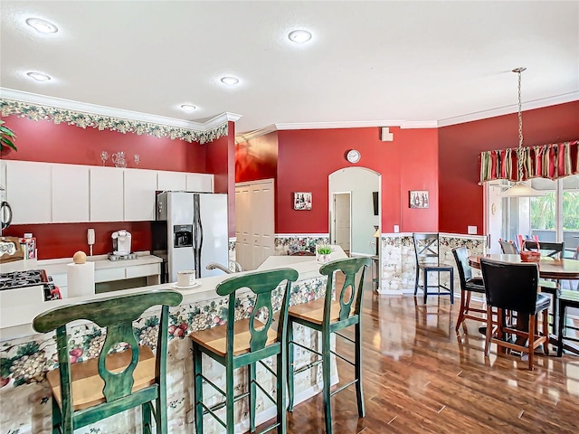 kitchen featuring appliances with stainless steel finishes, dark hardwood / wood-style flooring, ornamental molding, decorative light fixtures, and white cabinetry