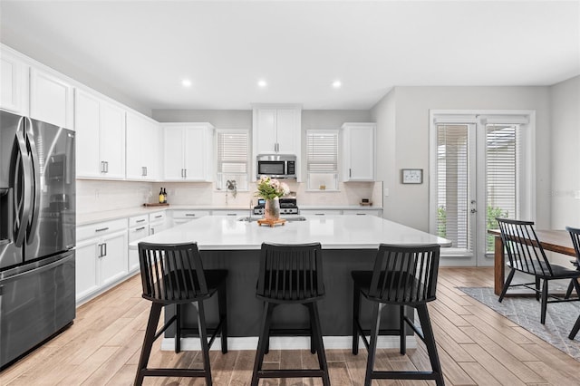 kitchen with plenty of natural light, a kitchen island, white cabinetry, and appliances with stainless steel finishes