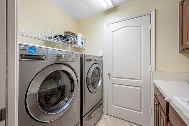 washroom with light tile patterned flooring, cabinets, separate washer and dryer, and a textured ceiling