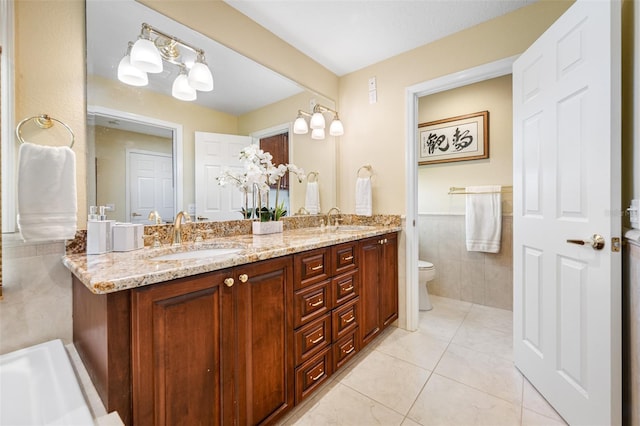 bathroom with tile patterned flooring, vanity, toilet, and tile walls