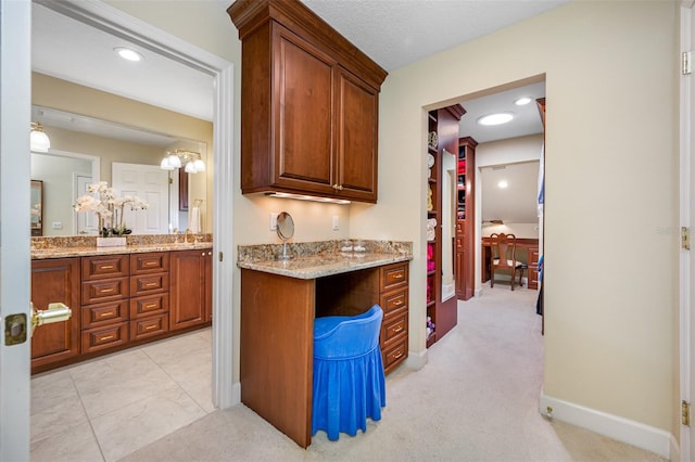 kitchen with light carpet, light stone countertops, and sink