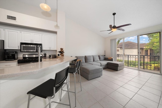 kitchen with high vaulted ceiling, white cabinets, range, and hanging light fixtures