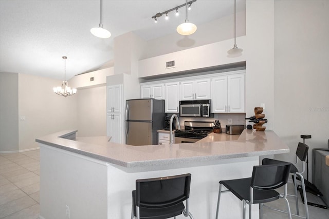 kitchen with white cabinetry, appliances with stainless steel finishes, a breakfast bar area, pendant lighting, and light tile flooring