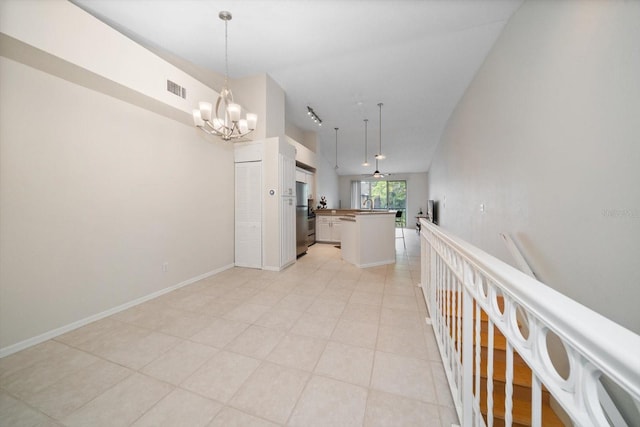 corridor featuring a notable chandelier and light tile floors