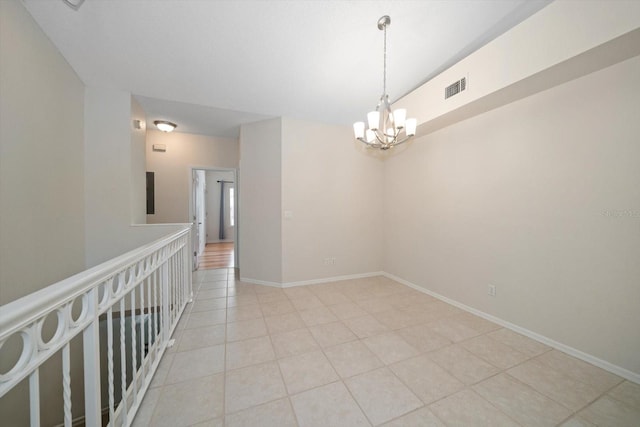 unfurnished room with light tile flooring and a chandelier