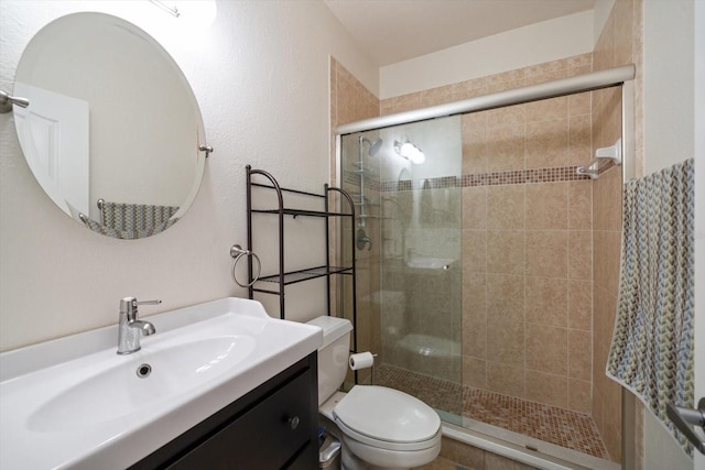 bathroom featuring a shower with shower door, toilet, and large vanity