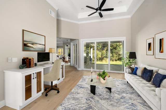 living room featuring light hardwood / wood-style floors, a raised ceiling, ceiling fan, and ornamental molding