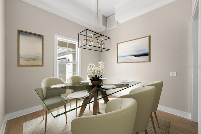 dining space featuring an inviting chandelier, ornamental molding, and hardwood / wood-style flooring