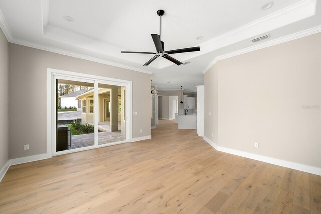 unfurnished living room featuring ceiling fan, ornamental molding, light hardwood / wood-style flooring, and a tray ceiling