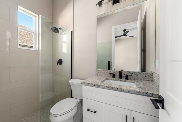 bathroom featuring ceiling fan, vanity, a shower with shower door, and toilet