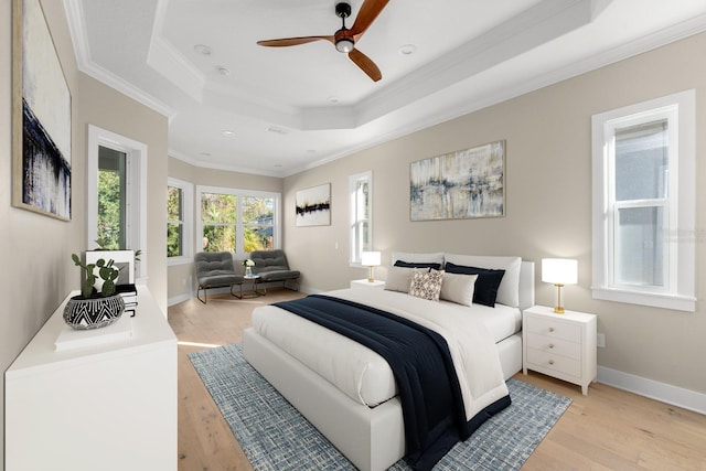 bedroom with ceiling fan, light hardwood / wood-style floors, crown molding, and a tray ceiling