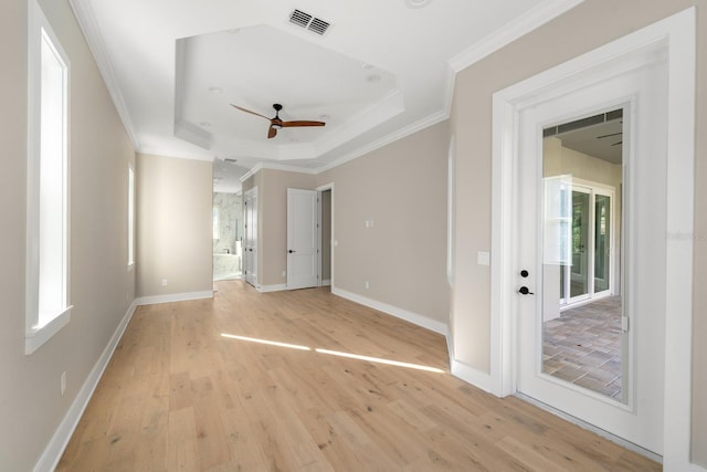 spare room with ceiling fan, ornamental molding, light hardwood / wood-style flooring, and a tray ceiling