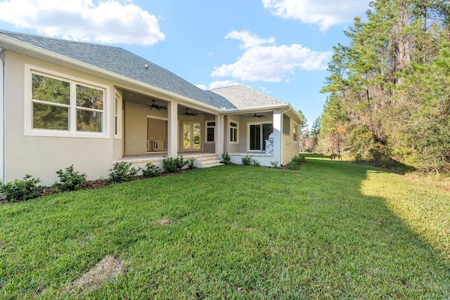 back of property with ceiling fan and a yard