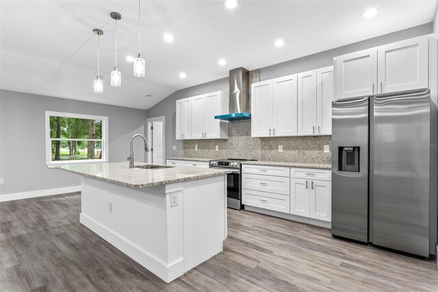 kitchen with white cabinetry, stainless steel appliances, sink, and wall chimney range hood